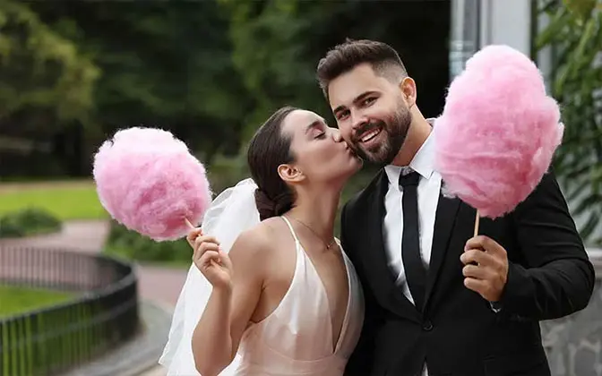 Pareja de novios celebrando con algodón de azúcar en boda